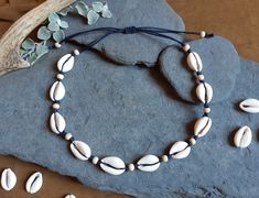 This necklace is handmade using large white cowrie shells, natural wooden beads and indigo waxed cotton cord. Ten shells are used for each necklace and the length is adjustable from a maximum of 65cm to a minimum of 35cm. THis necklace can also be made with genuine brown leather which you can select when you purchase this listing. Each necklace is made to order, so if you prefer a different color of the waxed cotton string you can feel free to send me a message and I will make it in the color of Surf Jewelry, Sea Jewelry, Shell Choker, Necklace Ideas, Handmade African, Cotton String, Jewelry For Men, Cowrie Shell, Shell Necklace