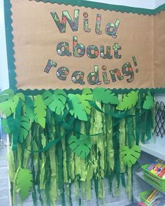 a bulletin board that says wild about reading with green paper leaves hanging from the front