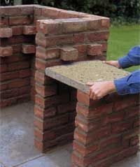 a man sitting at a table made out of bricks and cements with his hands on the edge