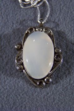 I am offering you this fabulous vintage sterling silver (stamped) extra large mother of pearl pendant charm and necklace chain. It features a gorgeous huge oval shaped setting , with spectacular large stone coverage. It has a bezel setting, to enhance this marvelous sterling silver setting the artist added lots curved lines.... Really giving this ring such allure and interest. It measures a very bold 1 3/4 inch by 1 inch The necklace chain is a very sturdy box link chain, that measures a very ve Vintage White Gemstone Necklaces, Vintage White Gemstone Necklace, White Vintage Gemstone Necklace, Elegant Oval Necklace With Large Stone, Antique Silver Oval Necklace, Silver Oval Pendant Costume Jewelry, Silver Oval Costume Jewelry Necklace, Vintage Oval Sterling Silver Necklaces, Vintage Oval Jewelry With Large Stone