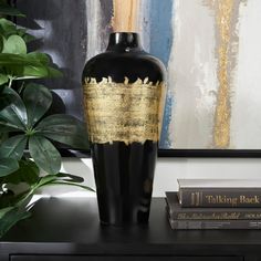 a black and gold vase sitting on top of a table next to a book shelf