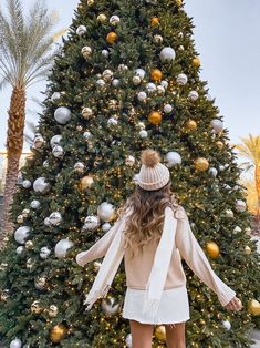 a woman standing in front of a christmas tree