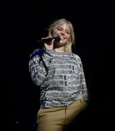 a woman standing in front of a microphone and singing into a microphone with her mouth open