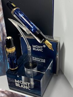 a fountain pen sitting on top of a blue box next to a bottle of liquid