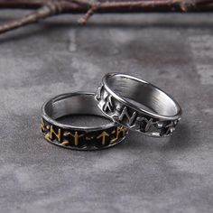 two silver rings with gold crosses on them sitting on a gray surface next to twigs