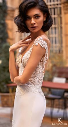 a woman in a wedding dress posing for the camera with her hand on her shoulder