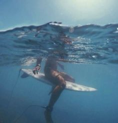 a man riding on top of a white surfboard under water