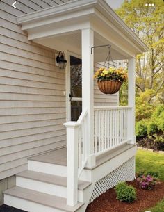 a porch with white railing and flower pot on the front steps, next to a house