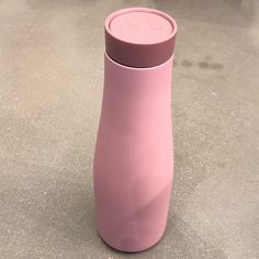 a pink vase sitting on top of a cement floor