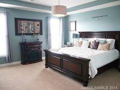 a bedroom with blue walls and white bedding in the center is decorated with wood furniture