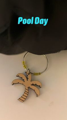 a wooden keychain with a palm tree on it and the words pool day written in blue