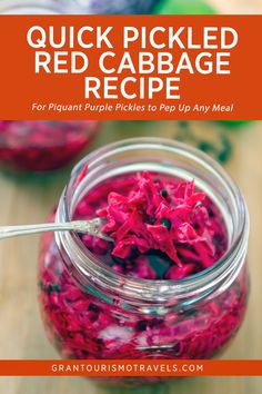 a jar filled with red cabbage on top of a wooden table next to a spoon