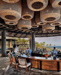 people are sitting at a bar with wicker hanging from the ceiling