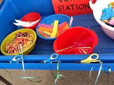 there are many different bowls and scissors on the blue trays that have paper clips in them