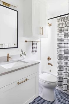 a white toilet sitting next to a sink in a bathroom under a mirror and shower curtain