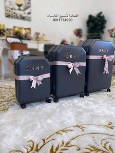 three black suitcases with pink bows and name written on the handles are sitting on a carpet