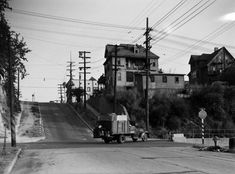 an old black and white photo of a truck driving down the road