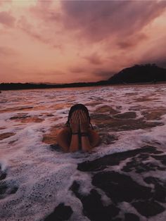 a woman laying on top of a sandy beach under a cloudy sky