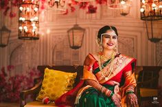 a woman sitting on top of a couch wearing a green and red sari dress