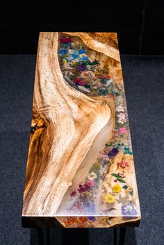 a wooden table with flowers painted on the top and bottom, sitting on carpeted flooring