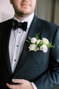 a man in a tuxedo is wearing a boutonniere with white flowers