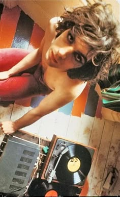 a woman is posing next to an old record player