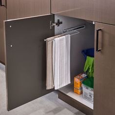 an open cabinet in a bathroom with towels and other items on the shelf below it