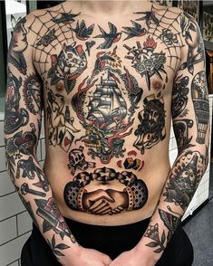 a man with lots of tattoos on his chest and hands in front of the chest