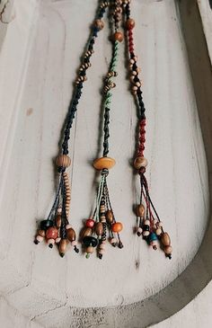 several necklaces are hanging on the side of a white door with wood bead details