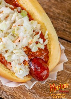 a hot dog with onions and ketchup in a bun on a wooden table