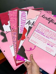 a person is holding up pink papers with writing on them and the paper has been cut out