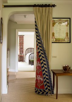 an open door with curtains hanging from it's sides and a table in the background