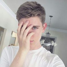 a young man holding his hand to his face in front of the mirror with one eye open