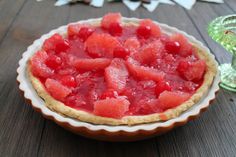 a watermelon pie sitting on top of a wooden table next to a glass vase