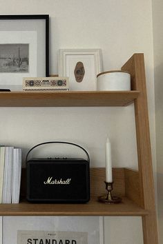 a shelf filled with books and other items on top of a wooden shelf next to a candle