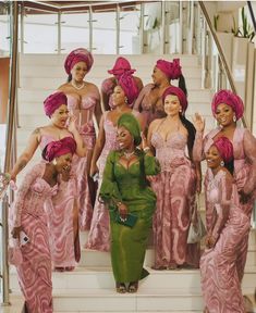 a group of women dressed in pink and green outfits standing on steps with each other