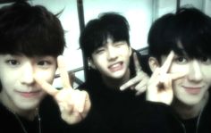 three young men posing for the camera with their fingers in the shape of two peace signs