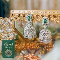 Lose yourself in the gleaming beauty of the Aymah Earrings! A versatile pair of earrings crafted with CZ stones and an emerald accent. Approximate earrings length is 2.6". Silver-plated on high-quality brass as base metal. In-stock & ready-to-ship. *Please Note: We use faux stones and beads in all of our jewelry. Emerald Drop Diamond Earrings For Wedding, Hand Set Emerald Earrings For Party, Green Cubic Zirconia Earrings For Celebration, Hand Set Green Cubic Zirconia Earrings, Green Cubic Zirconia Hand Set Earrings, Emerald Chandbali Earrings For Wedding, Emerald Diamond Earrings For Wedding, Green Diamond Earrings With Intricate Design, Silver Jeweled Jhumkas For Gifting