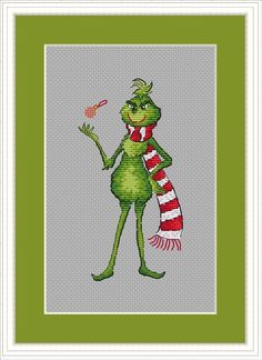 a cross stitch picture of a green frog holding a red and white striped scarf,