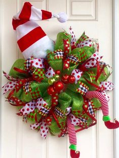 a christmas wreath on the front door with santa's hat and candy canes