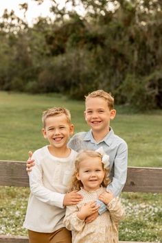 two boys and a girl standing on a fence