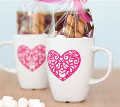 two coffee mugs with marshmallows in them and a pink bow on top