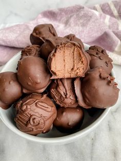 a white bowl filled with chocolate truffles on top of a marble countertop