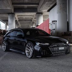 the black car is parked under an overpass