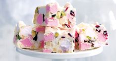 a white plate topped with pieces of cake covered in pink and green frosting on top of a table