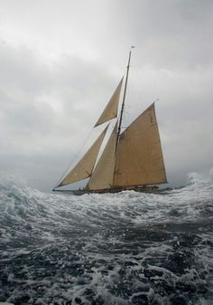 a sailboat in the middle of an ocean with rough waves on it's sides