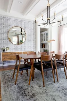 a dining room table with six chairs and a round mirror on the wall