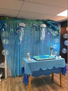 a blue table topped with a cake and balloons