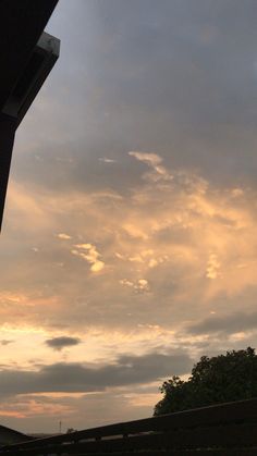 the sky is filled with clouds as the sun goes down in the distance behind some buildings