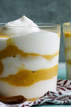 two glasses filled with dessert sitting on top of a table